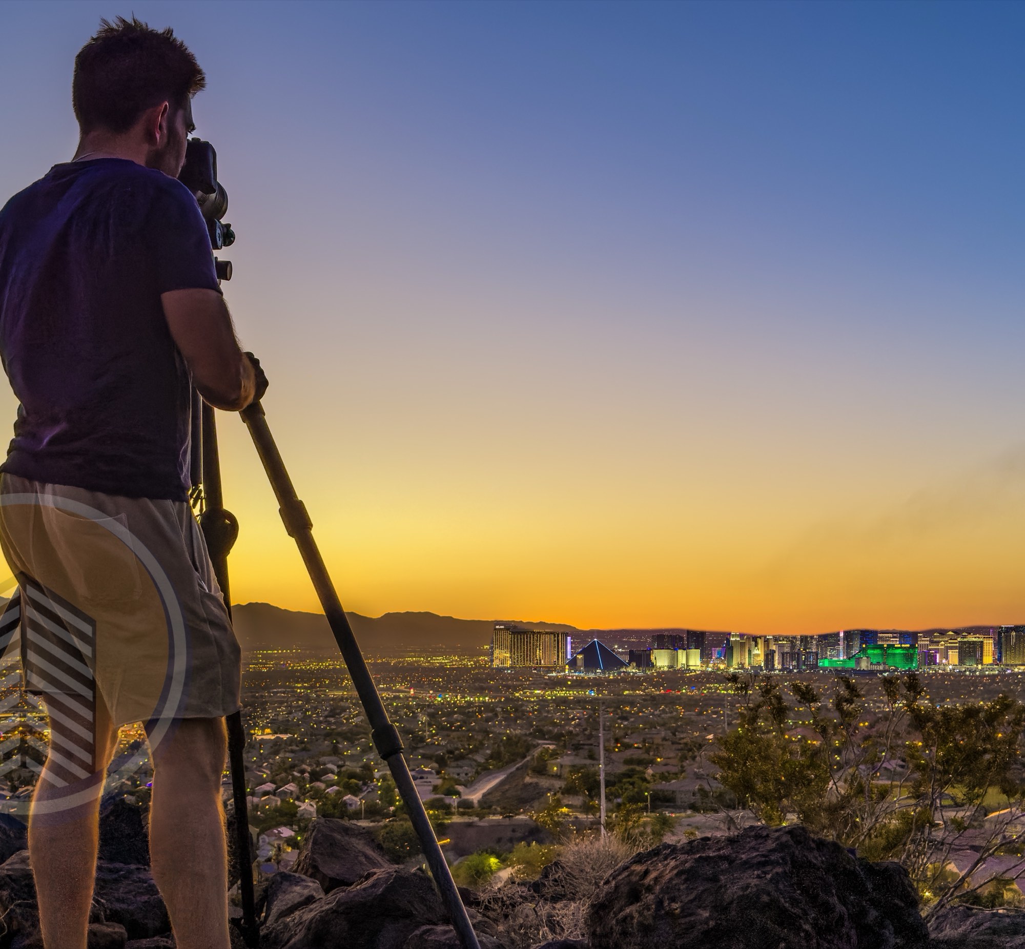 Zach Mirer at a tripod photographing the Las Vegas Strip at dusk from a rocky overlook above the valley